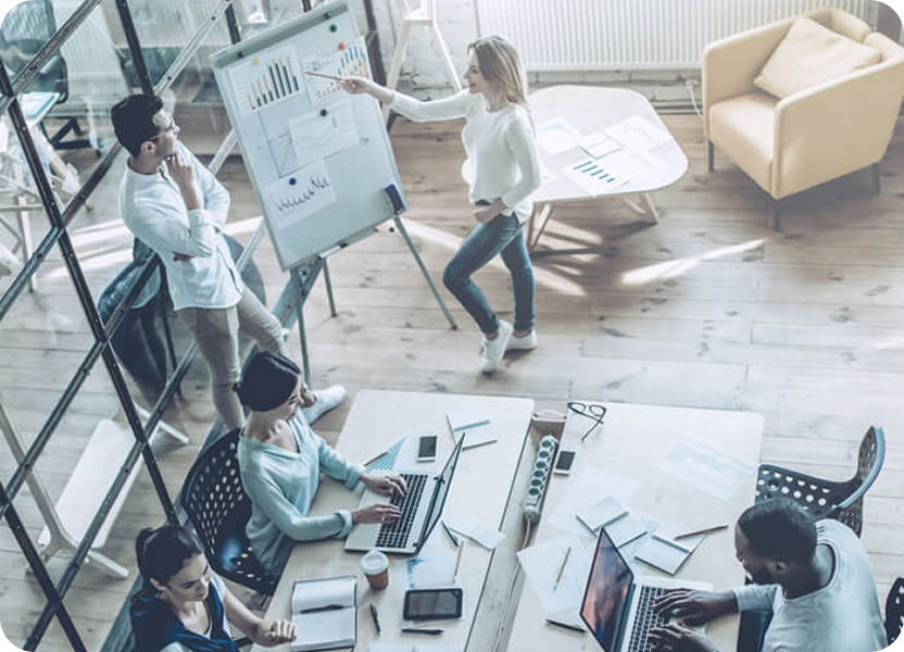  Equipe reunida em escritório moderno analisando gráficos em quadro branco.
