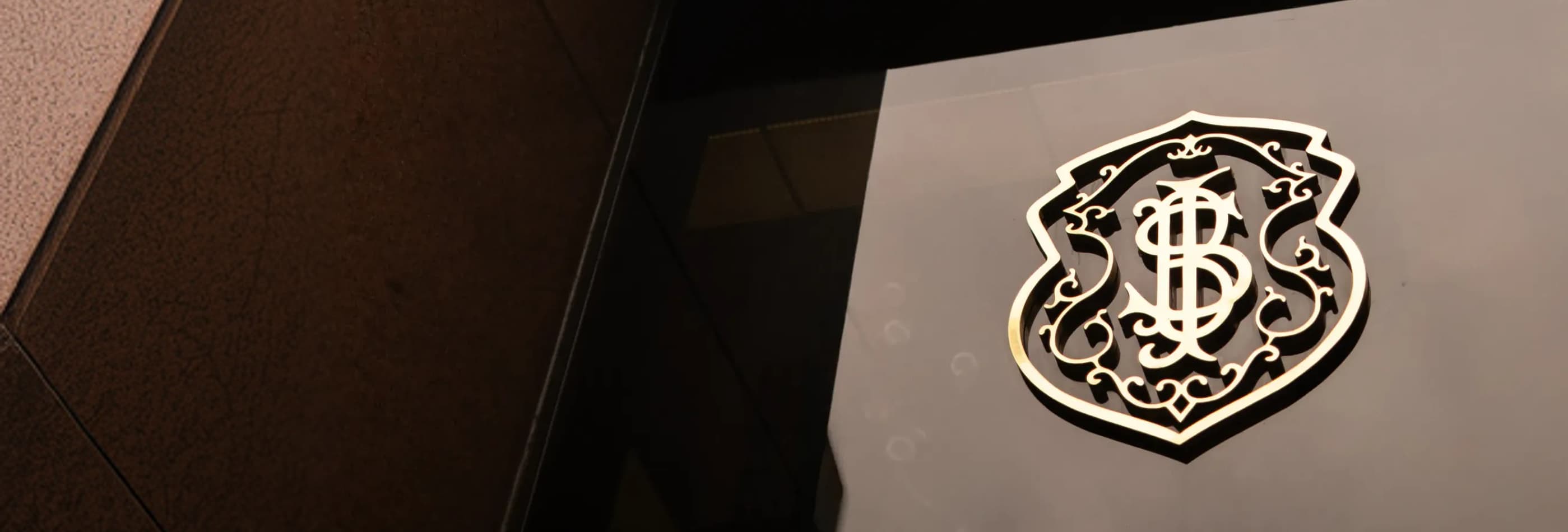 Logo dourado do Safra aplicado em fachada moderna com iluminação suave.