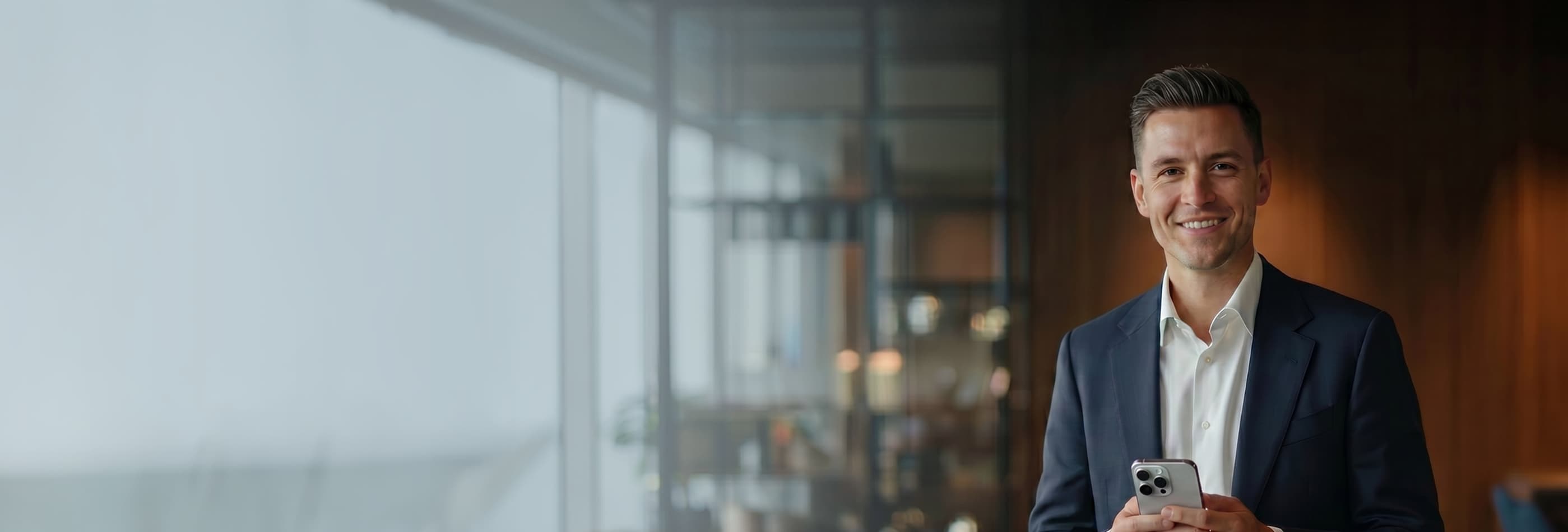 Homem de terno com celular em ambiente corporativo sofisticado.