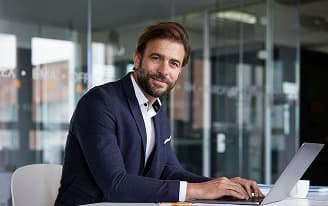 Homem de negócios sorrindo usando laptop em ambiente de escritório moderno